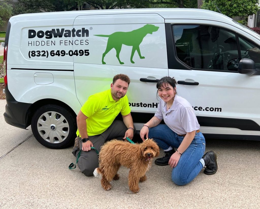 Jason and Keely from DogWatch of Houston posing in front of their van with customer Charlie the Goldendoodle