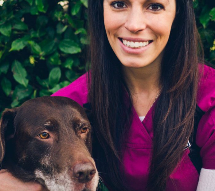 A girl hugging her dog and smiling