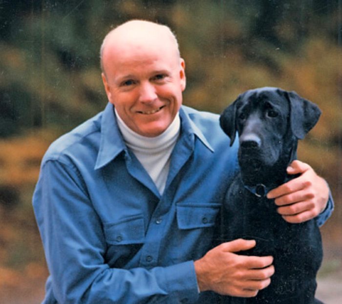 A man sitting and taking a picture with his dog