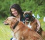 A girl sitting in a field with her 2 dogs